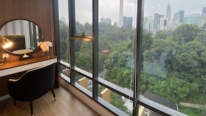 A modern room with a large window, a round mirror, a desk, and a chair.