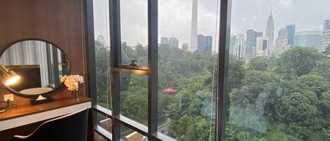 Una habitación moderna con un ventanal grande, un espejo redondo, un escritorio y una silla.