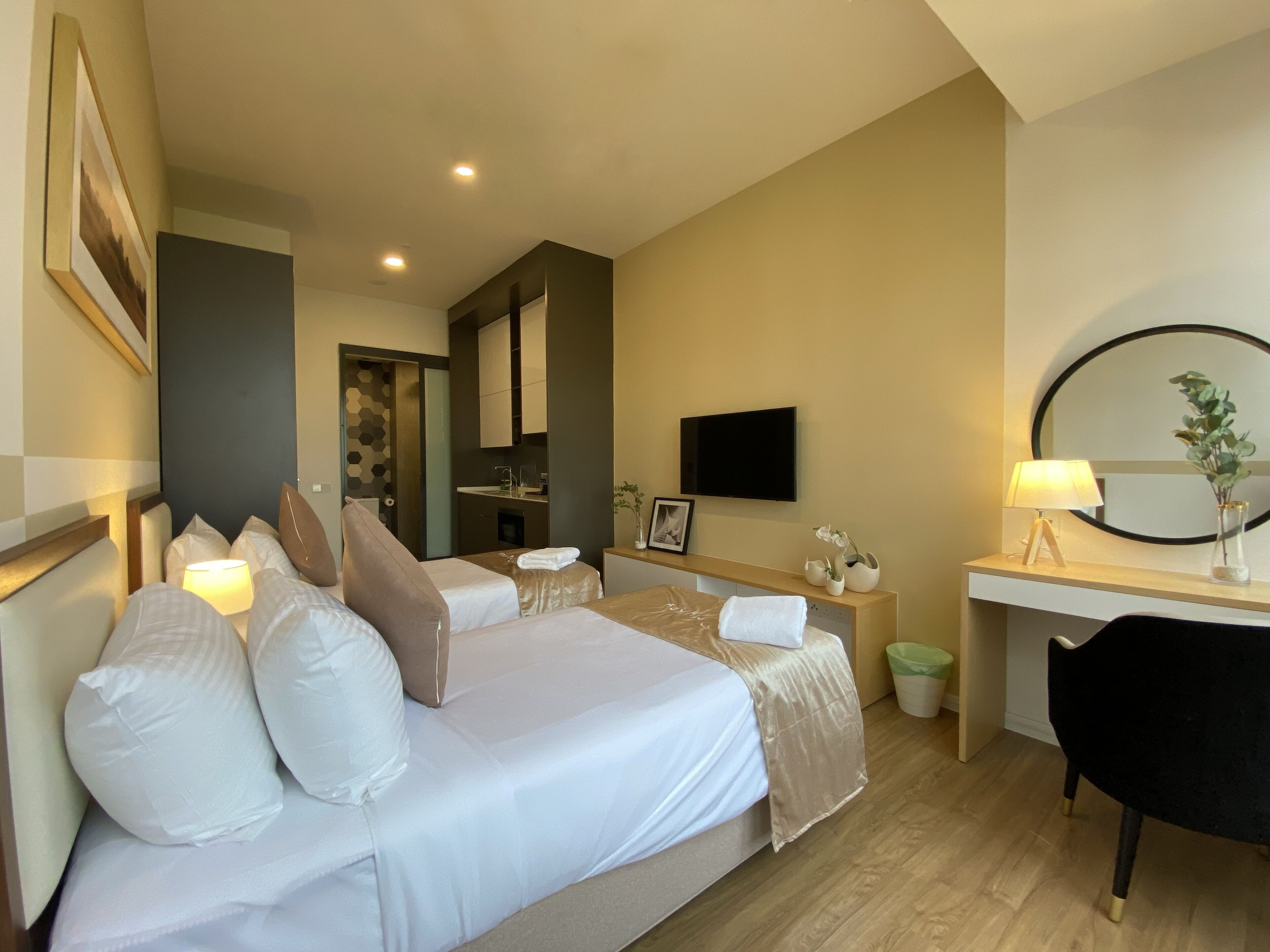 Une chambre d’hôtel comprenant un lit, des tables de chevet, un bureau, un miroir, une télévision et une petite salle de bain.