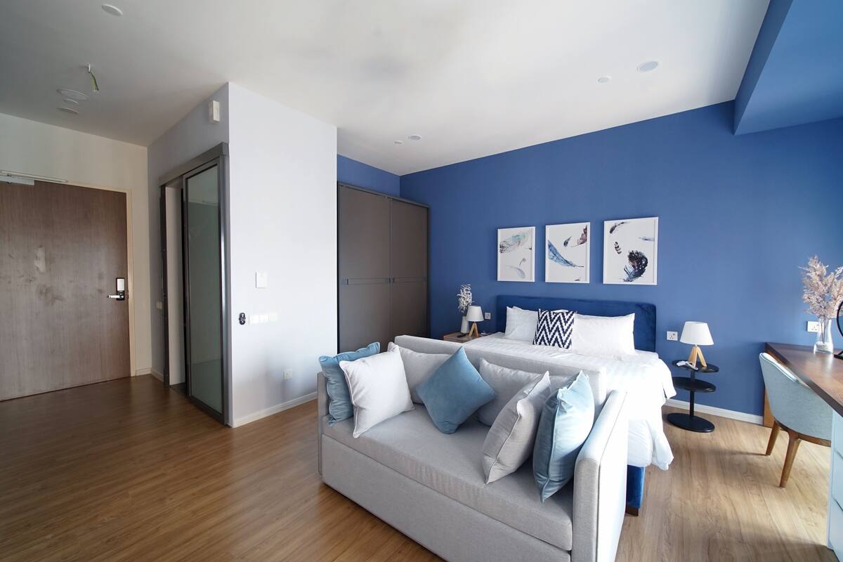 A modern bedroom with a bed, a sofa, and a desk.
