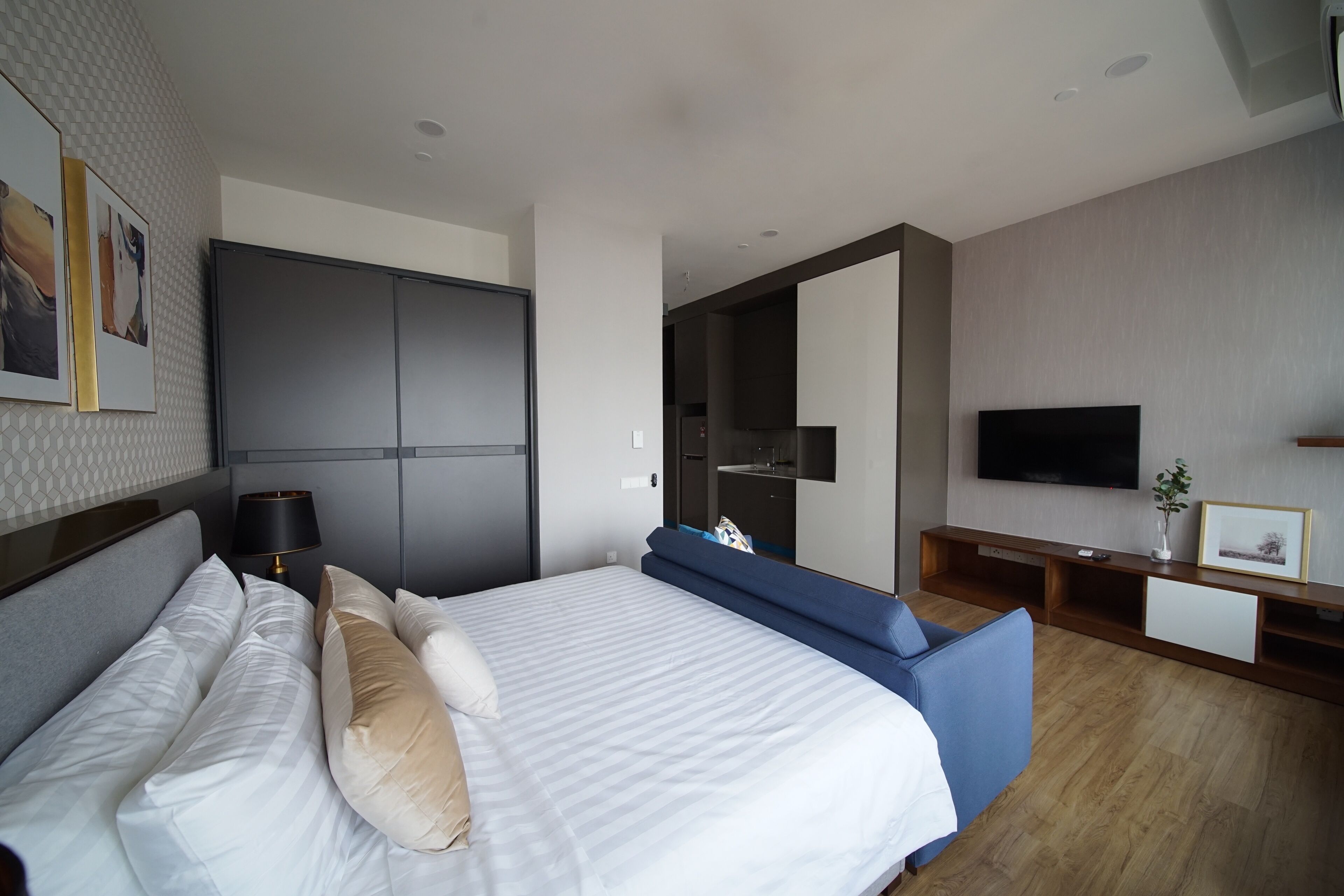 Una habitación de hotel moderna con una cama grande, televisor, armario y zona de estar.