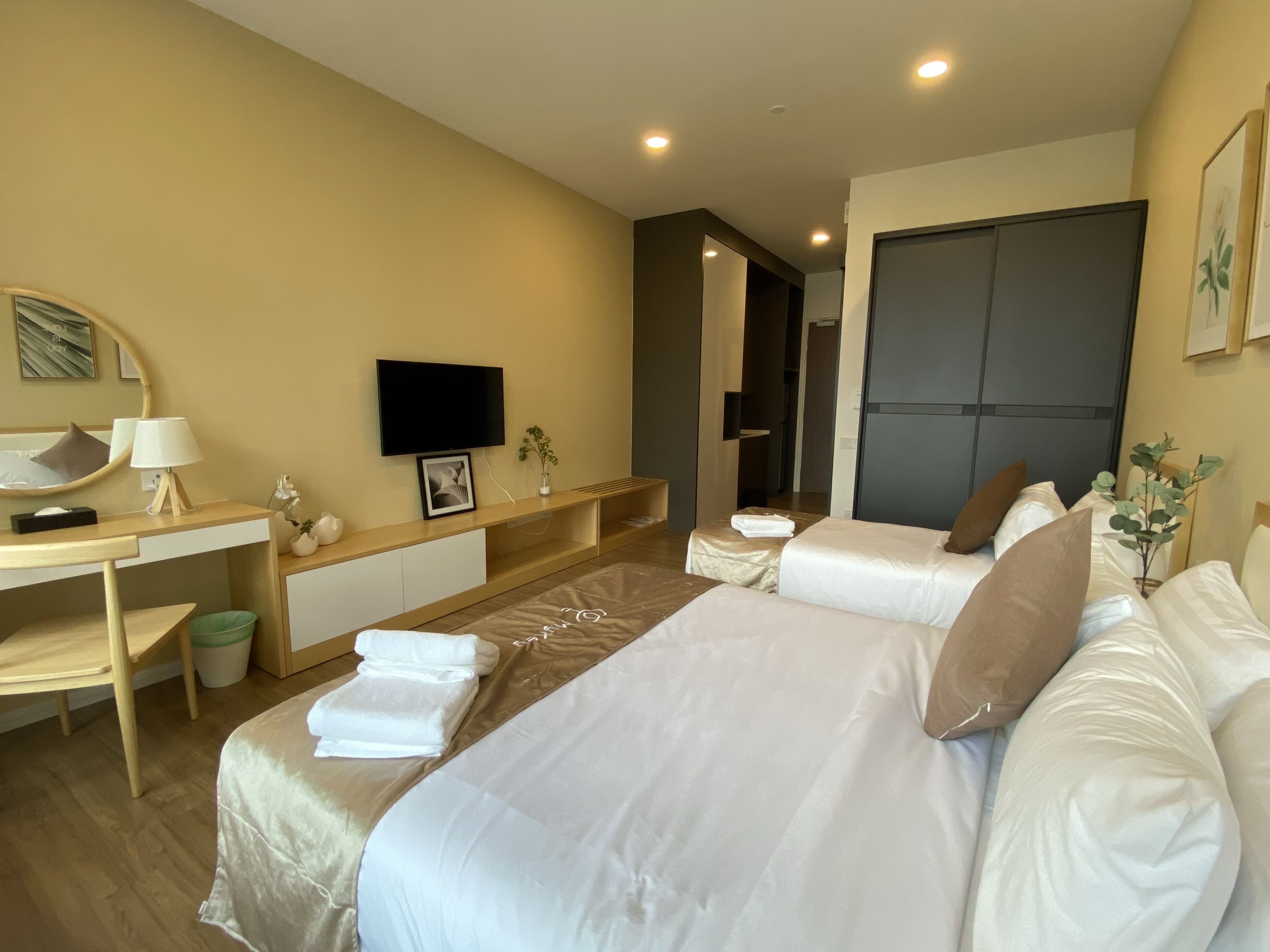 A hotel room with two beds, a desk, a chair, a TV, and a mirror.