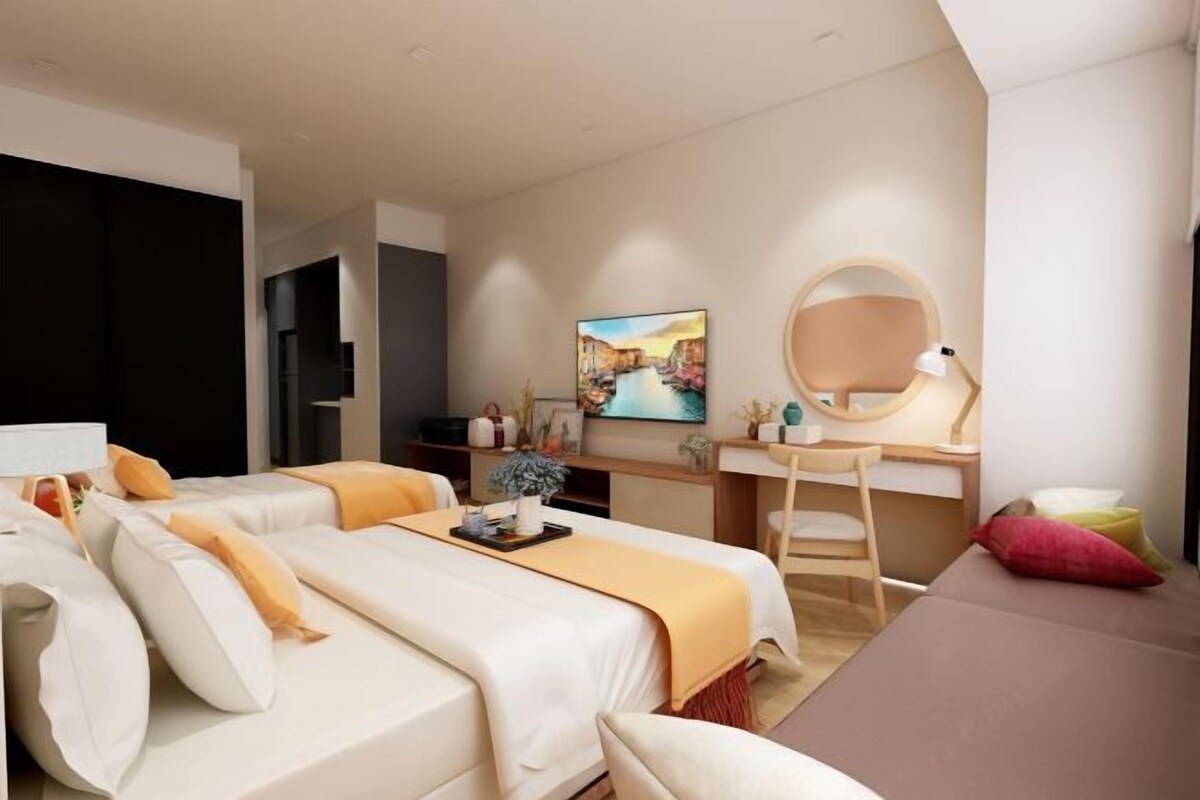 A modern hotel room with a large bed, a desk, a chair, and a TV.
