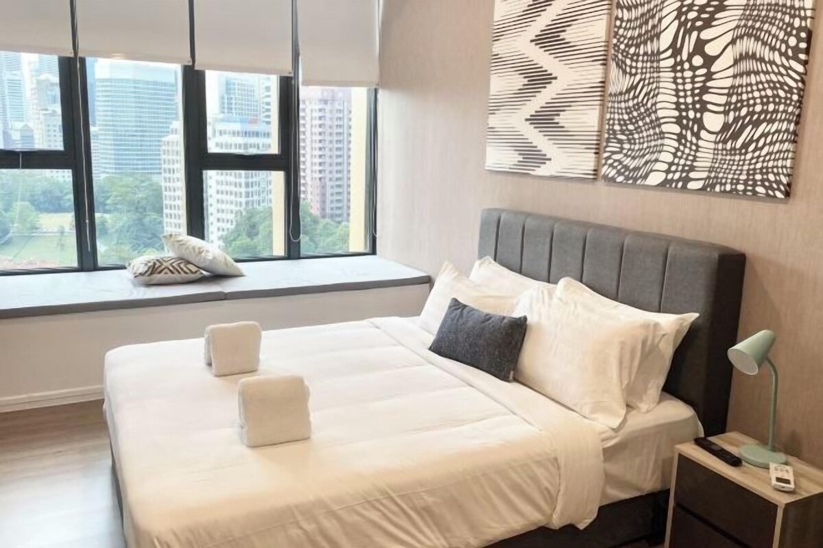 Una habitación de hotel moderna con una cama grande, una ventana con vistas a rascacielos y arte abstracto en la pared.