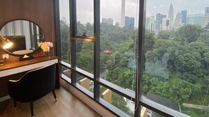 Una habitación moderna con un ventanal grande, un espejo redondo, un escritorio y una silla.