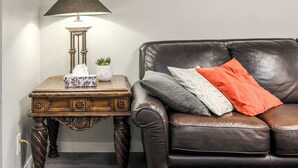 Un canapé en cuir marron avec un coussin, une table avec une lampe et une petite plante.