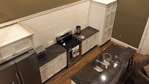 Una cocina moderna con armarios blancos, encimera de granito, electrodomésticos de acero inoxidable y ventana con vistas.