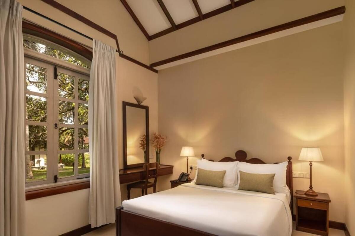 A hotel room with a bed, bedside lamps, a desk, and a window with curtains.