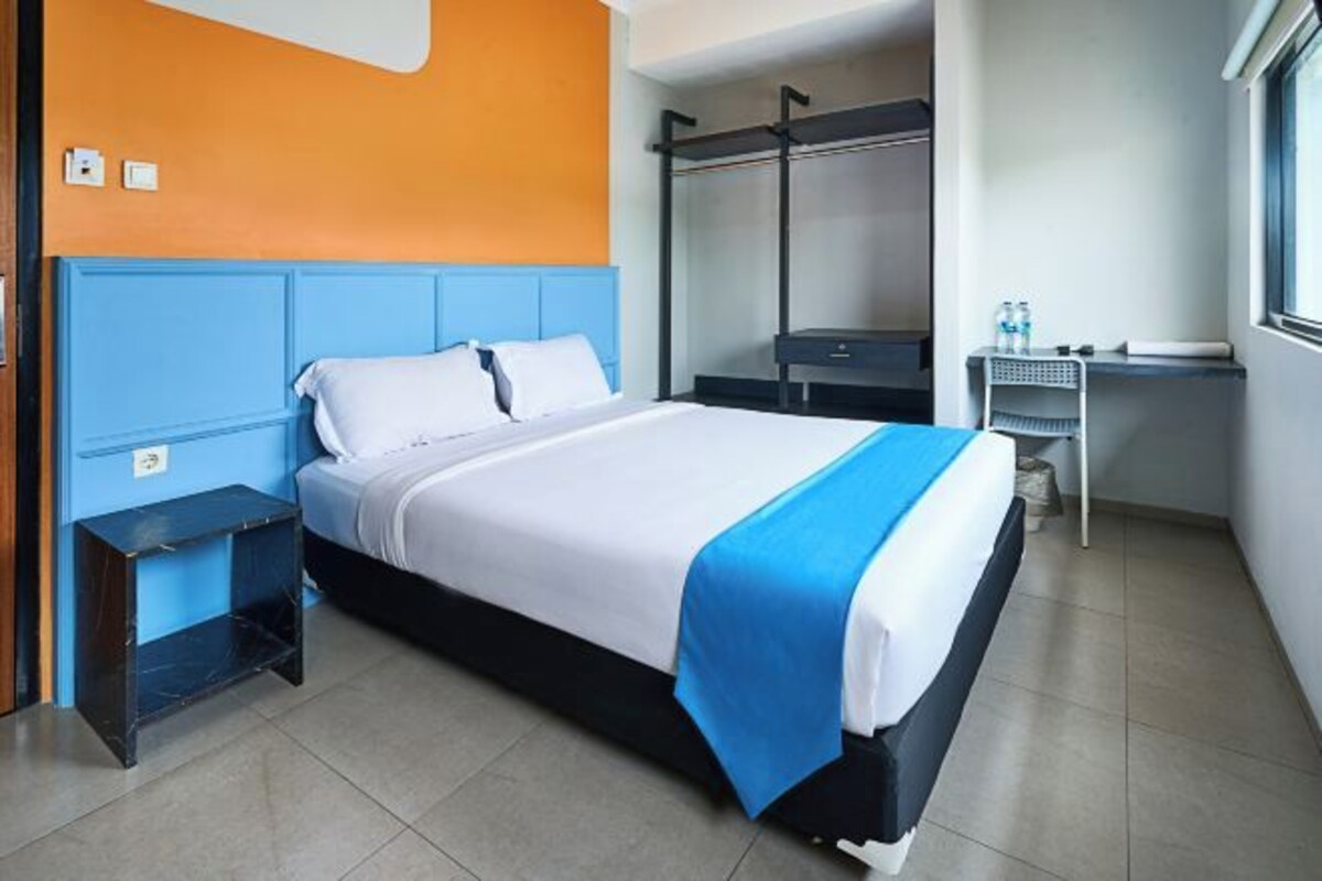 A hotel room with a bed, a desk, and a wardrobe.