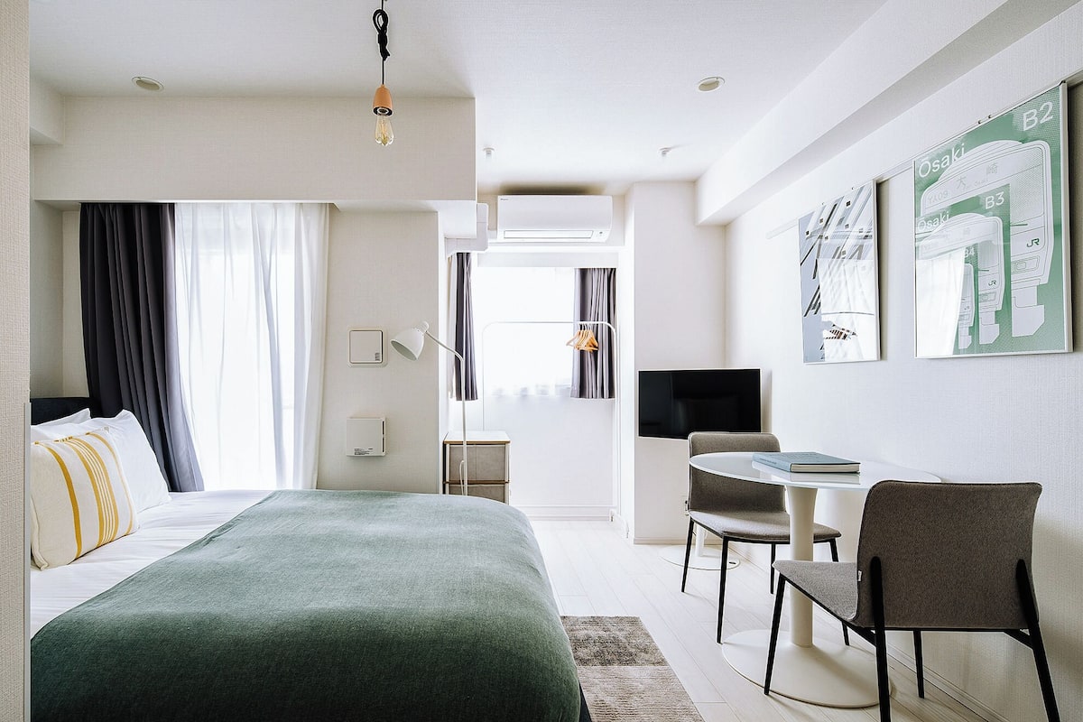 Quarto de hotel moderno com cama, escrivaninha, cadeira e obra de arte na parede.