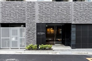 A modern building facade with a stone-textured exterior and a sign reading "SECTION L GINZA EAST". - Section L Ginza East (Tokyo)