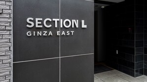 Ein Schild mit der Aufschrift "SECTION L GINZA EAST" an einer Gebäudefassade.