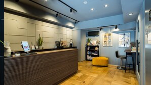 Ein moderner Empfangsbereich mit einem Holzbüro, einem gelben Hocker und einer Bar mit einem schwarzen Stuhl.