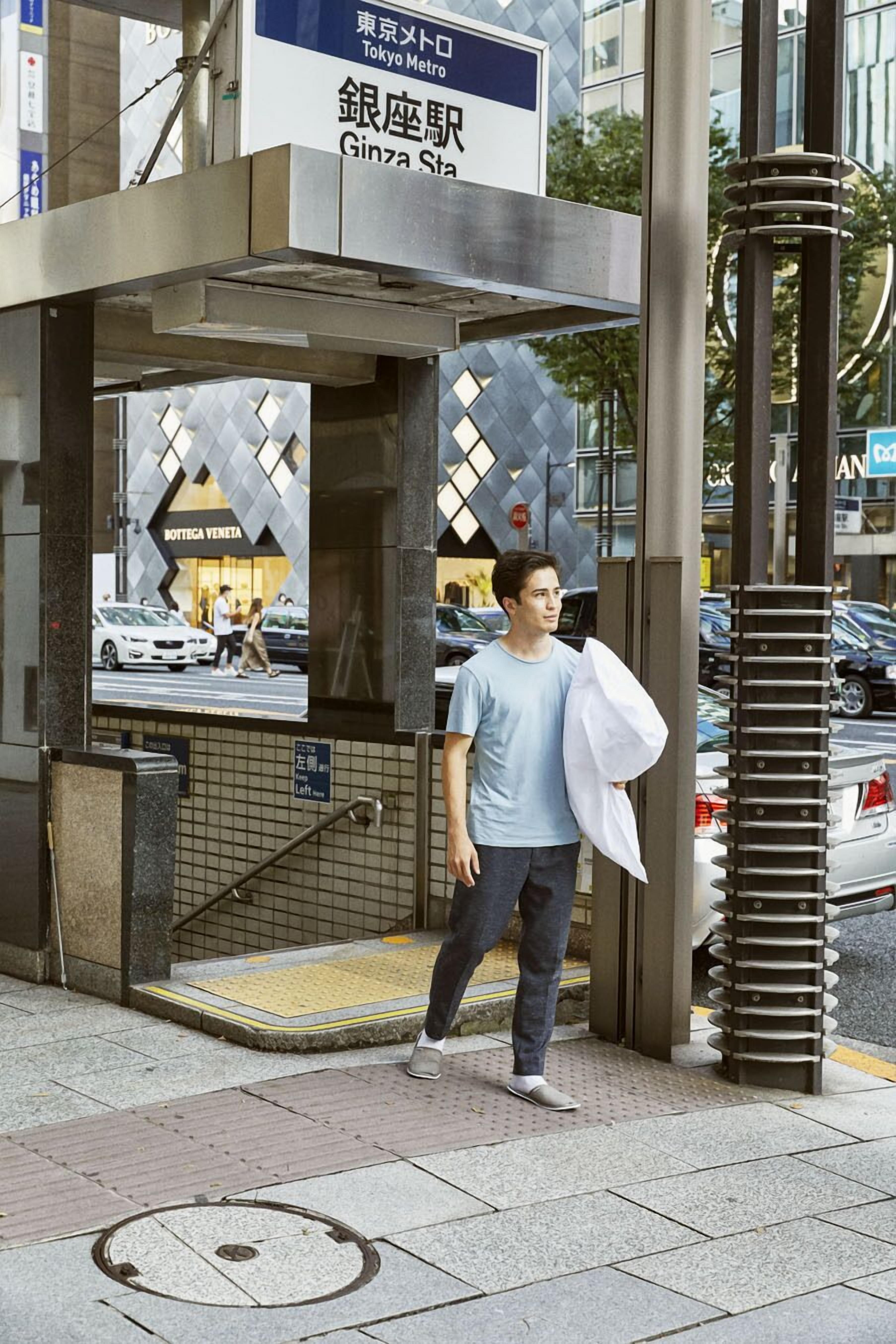 Un homme passe devant l’entrée de la station de Ginza, une veste blanche jetée sur l’épaule.