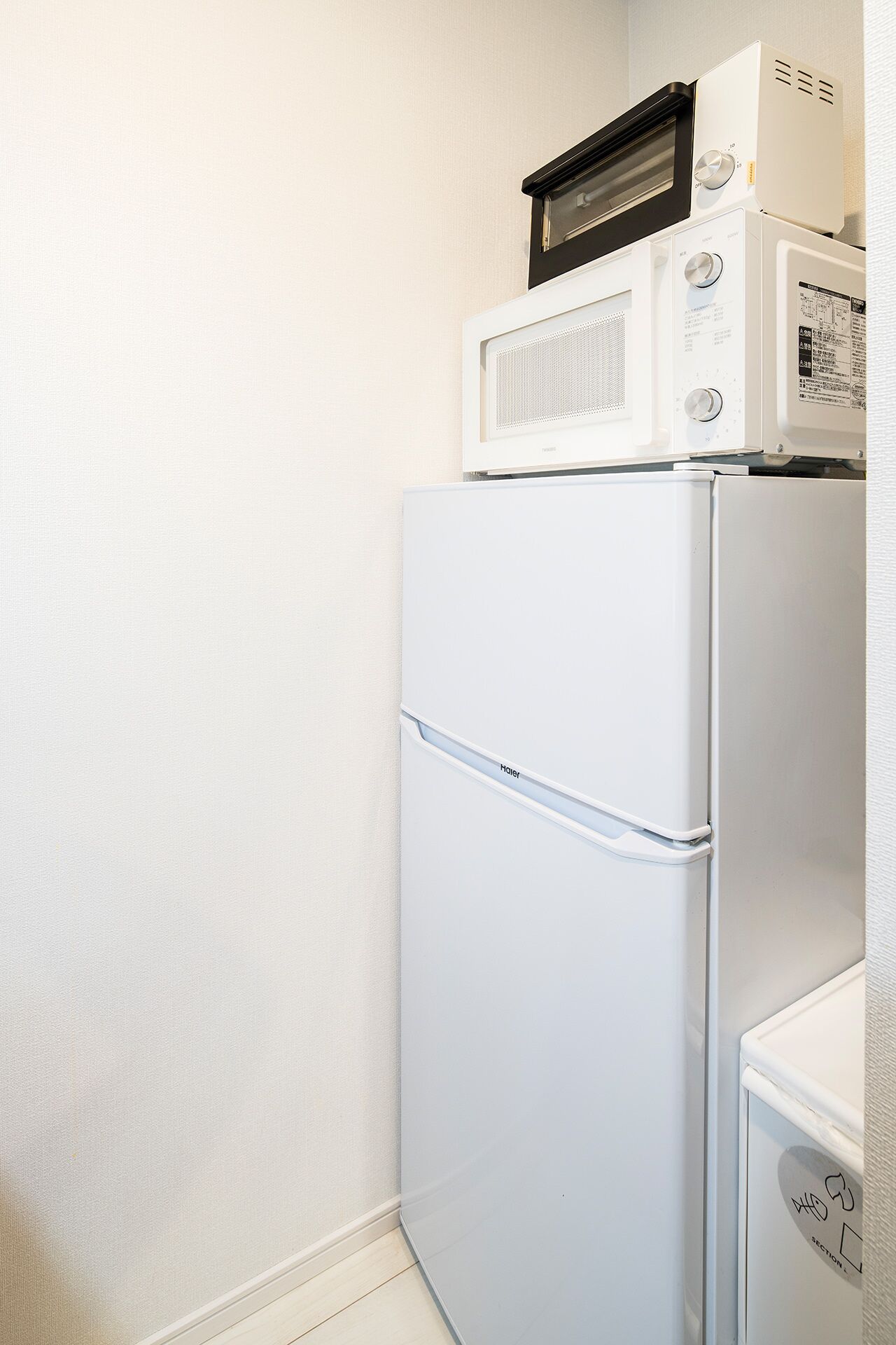 A compact kitchenette with a white refrigerator, a microwave, and a small oven.