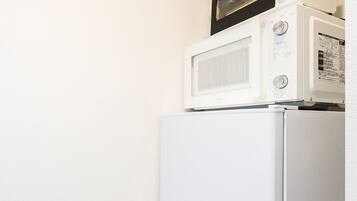A compact kitchenette with a white refrigerator, a microwave, and a small oven.