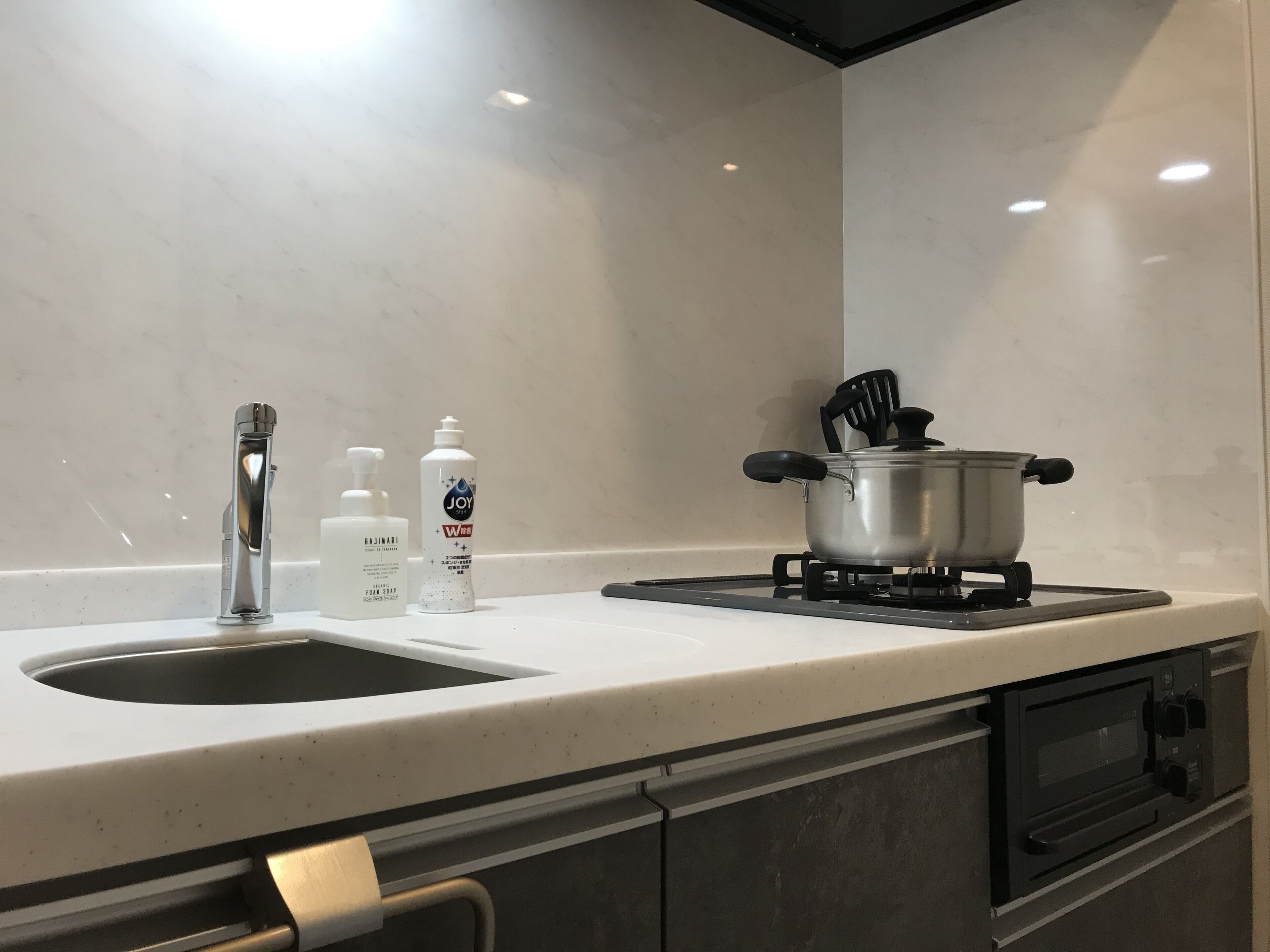 Una cucina con un lavello doppio, un fornello e due flaconi di sapone.