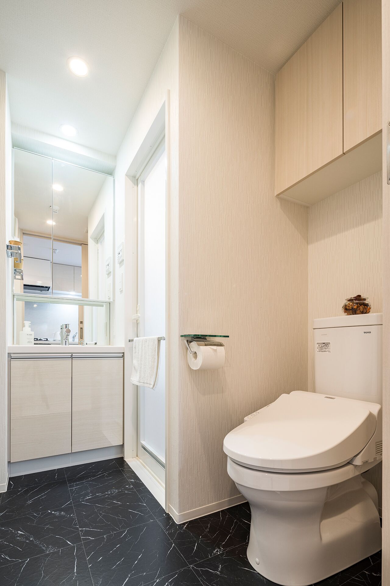 A modern bathroom with a toilet, a sink, and a mirror.