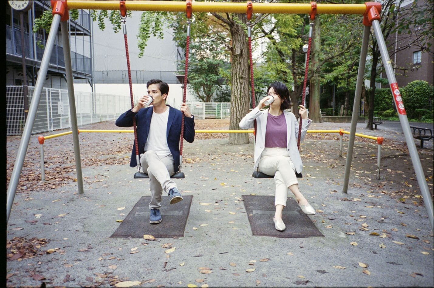 A park with swings and a clock in the background.