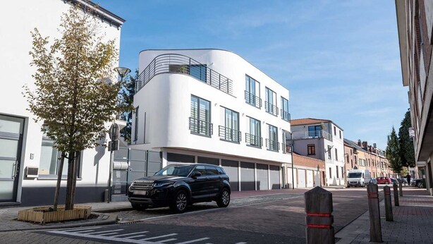 A modern building with a curved facade, large windows, and a garage. - Studio Brussels Airport (Zaventem)