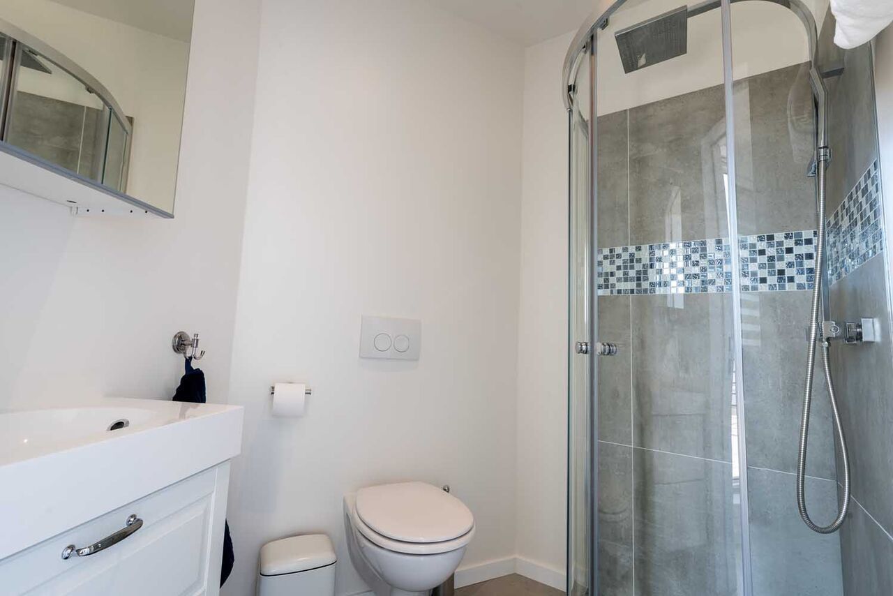 A modern bathroom with a glass-enclosed shower, a white sink, and a toilet.
