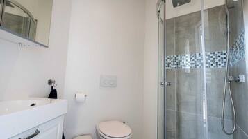 A modern bathroom with a glass-enclosed shower, a white sink, and a toilet.