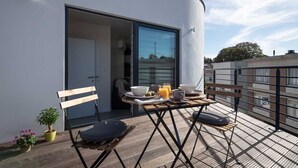 A balcony with a table set for breakfast, a chair, and a potted plant. - Studio Brussels Airport (Zaventem)