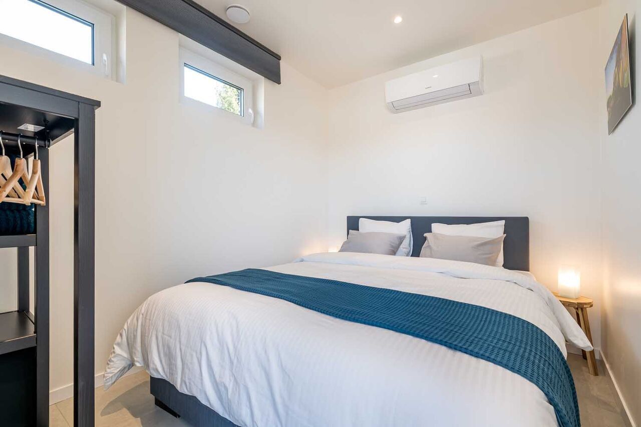 A bedroom with a bed, a wardrobe, and an air conditioning unit.