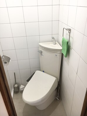 A small, white bathroom with a toilet, a sink, and a green towel hanging on the wall. - Step Pier (Onomichi)