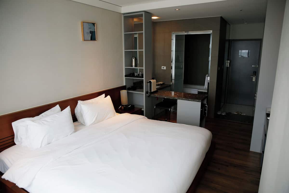 Une chambre d’hôtel avec un grand lit, un bureau avec une chaise, un miroir et une armoire.