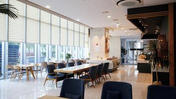 A spacious indoor area with large windows, a reception desk, and several tables and chairs arranged for dining or meetings.