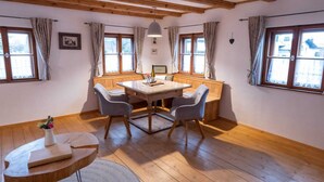 Un coin repas accueillant avec une table et des chaises en bois, un banc et une petite table ronde agrémentée d’un vase et d’un livre.