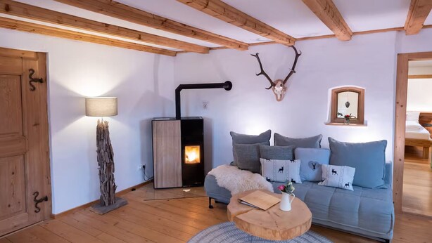 Un salon chaleureux avec un canapé, une table basse ronde en bois, une lampe et une cheminée.