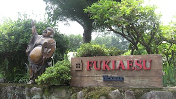 A welcome sign for FUKIAESU with a wooden backdrop and a sculpture.