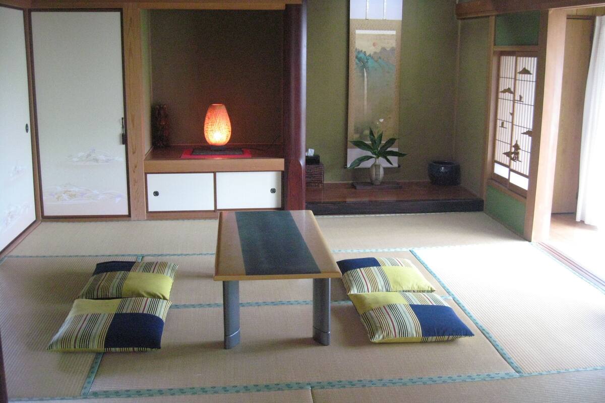 Une pièce de style japonais traditionnel, avec un sol recouvert de tatamis, une table basse, des coussins et des portes coulissantes.