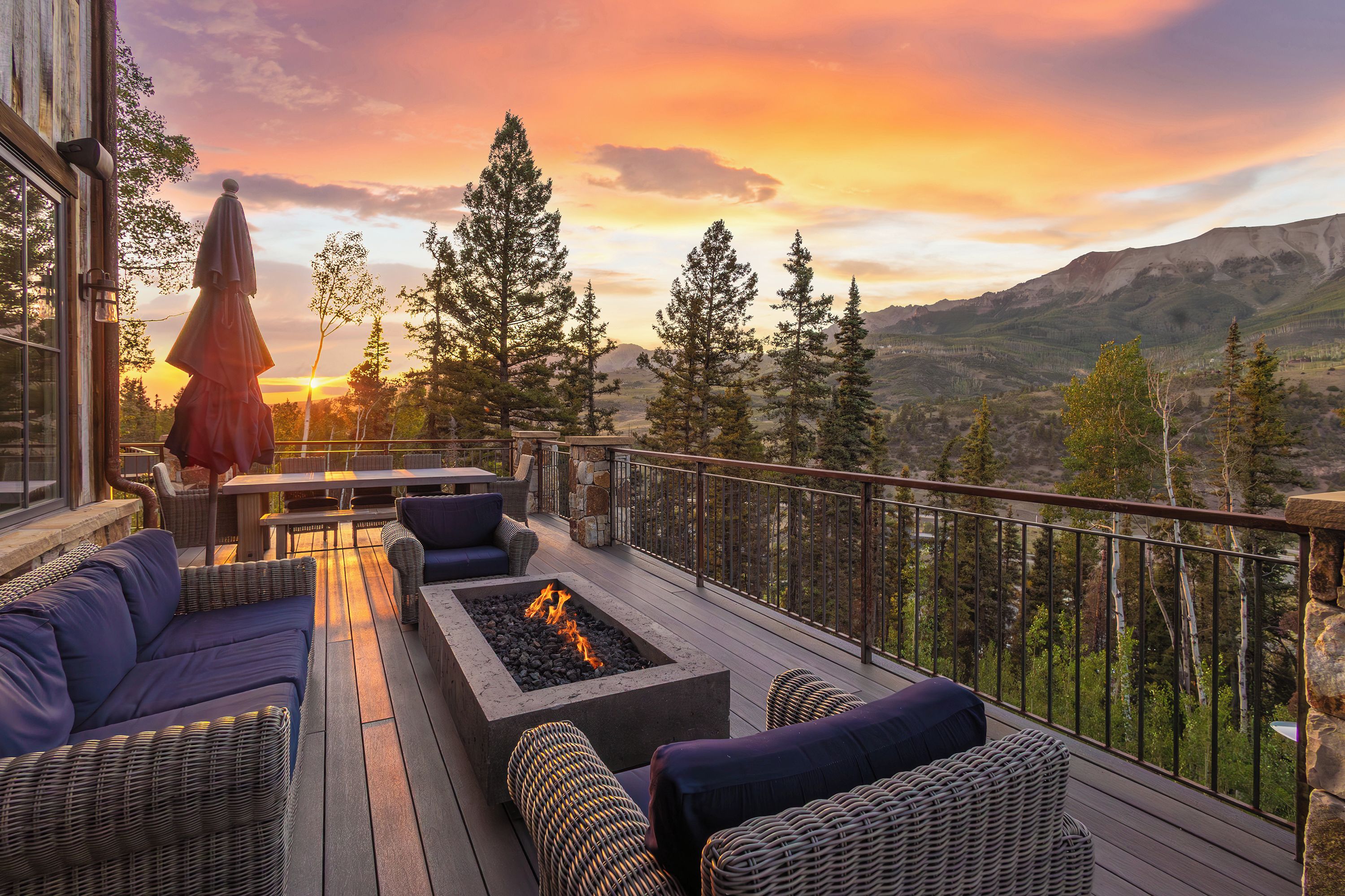 A deck with outdoor seating, a fire pit, and a view of mountains.