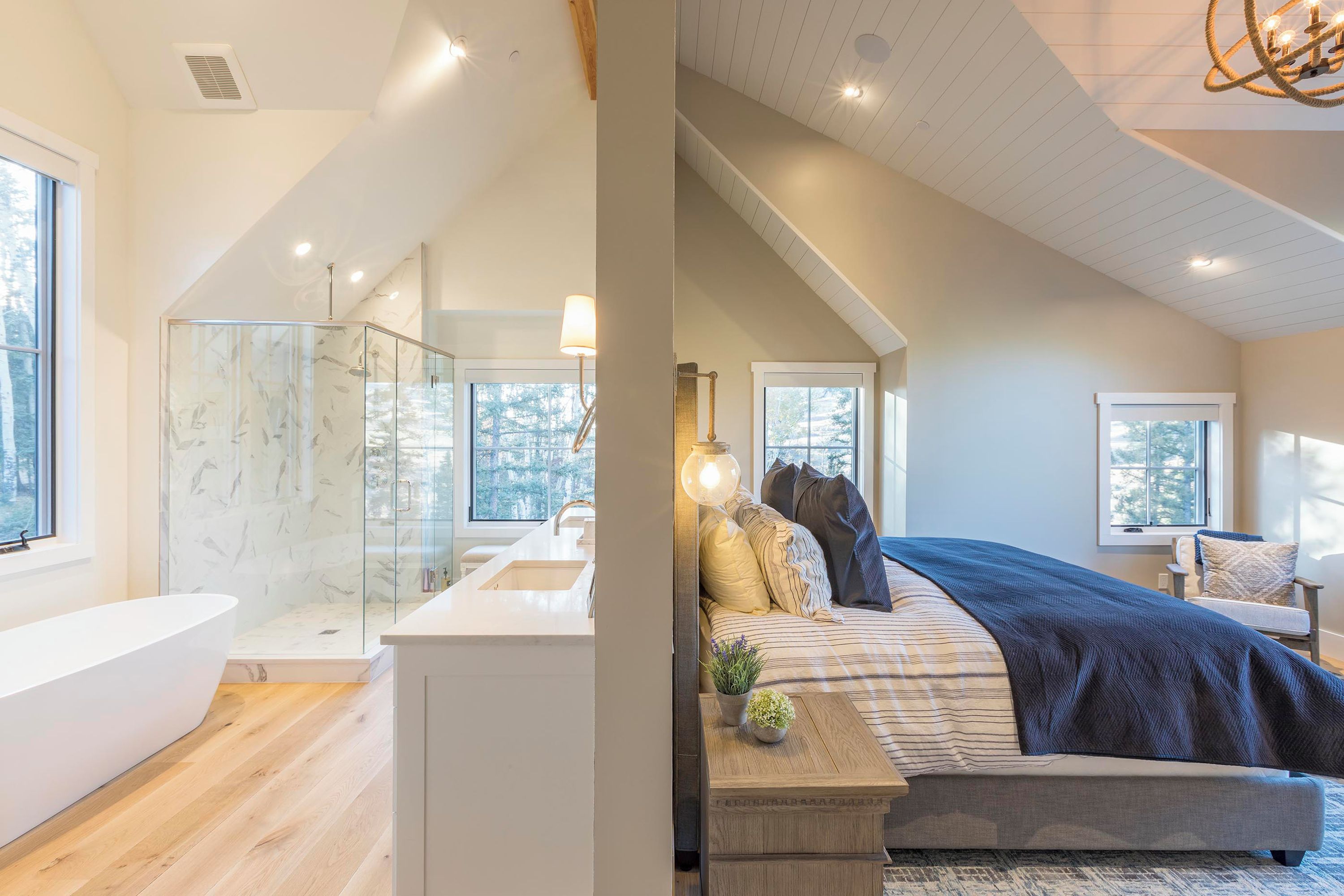 A modern bedroom with a large bed, a bedside table, and a window.