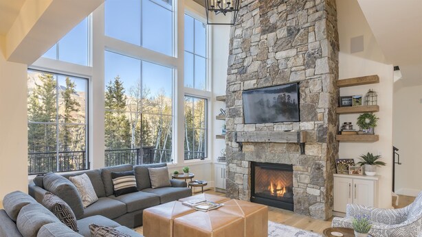 A spacious living room with a stone fireplace, large windows, and a cozy seating area. - OVERLOOK HAUS- Mountain Oasis Overlooking San Sophia’s Ridge, Fire Pit & Hot Tub (Mountain Village)