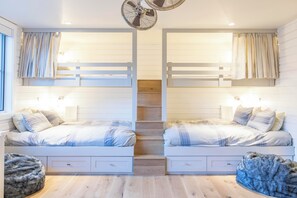 A room with two beds, a staircase, and a large window.