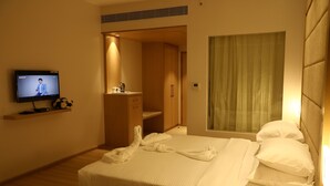 A hotel room with a bed, a TV, a wardrobe, and a window with curtains. - YN Hotels (Bengaluru)