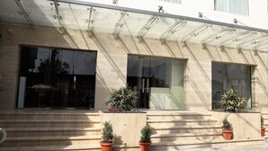 A building with a glass facade, large windows, and a set of steps leading to the entrance. - YN Hotels (Bengaluru)