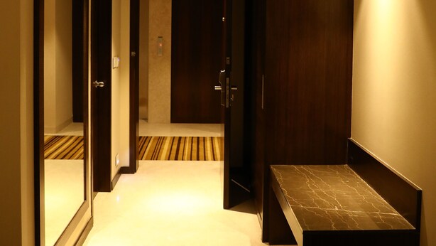 A hotel hallway with a carpeted floor, a bench, and a mirror on the left. - YN Hotels (Bengaluru)