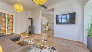 Una sala moderna con sofá, una mesa de centro y una chimenea. Hay un televisor montado en la pared y una estantería llena de libros.