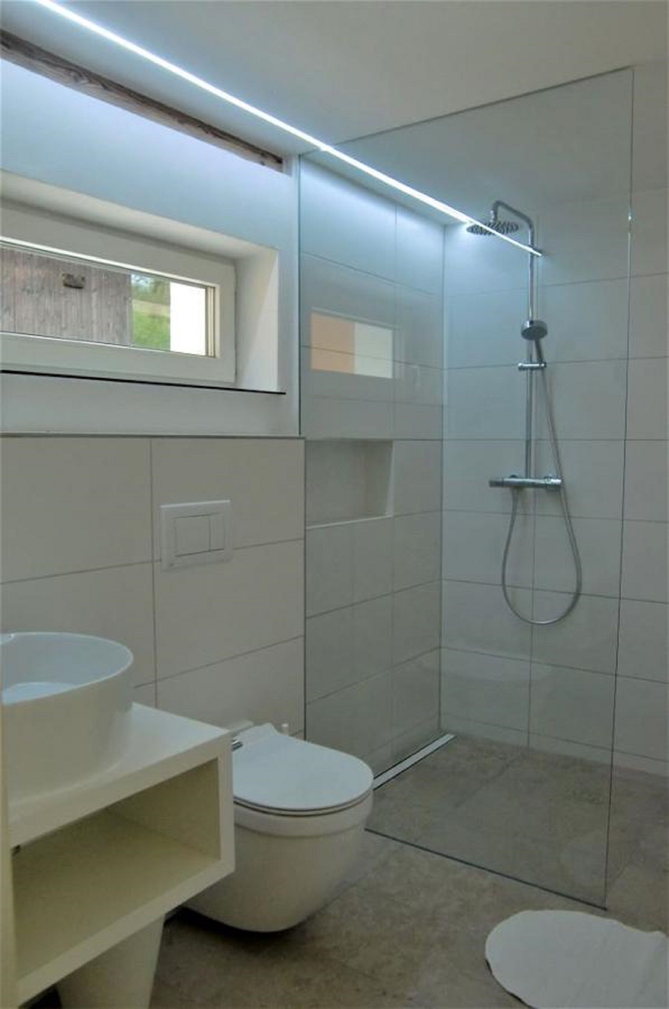 A modern bathroom with a toilet, a shower enclosure, and a vanity with a sink.