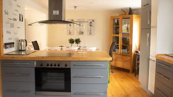 A modern kitchen with a central island, built-in oven, and a wooden cabinet with glass doors.