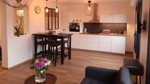 A modern kitchen with white cabinets, a dining area with a wooden table and chairs, and a living area with a sofa and a coffee table. - Apartment T3 located in front of the beach of QUIBERON. (QUIBERON)