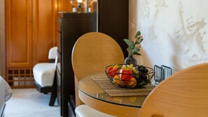 A dining area with a round glass table, a bowl of fruit, and a vase with flowers. - Villa Haroula (Parga)