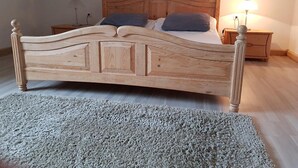 Un lit en bois avec une tête de lit, deux oreillers, une table de chevet et une lampe.