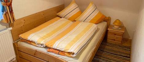 Una cama de madera con ropa de cama a rayas y una mesita de noche con una lámpara.