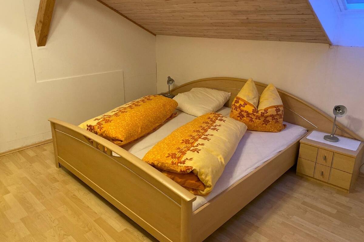 Ein Einzelbett mit Holz Kopfteil und Nachttisch mit Lampe.